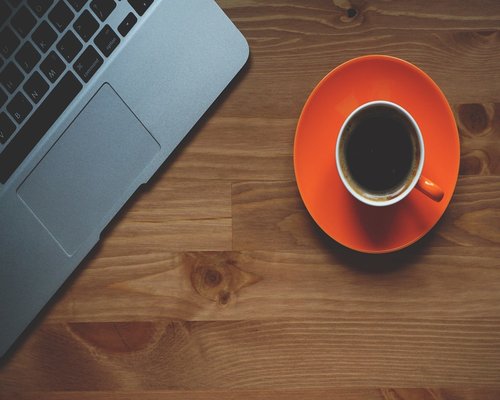 A tired person sitting at a desk with too many coffee cups